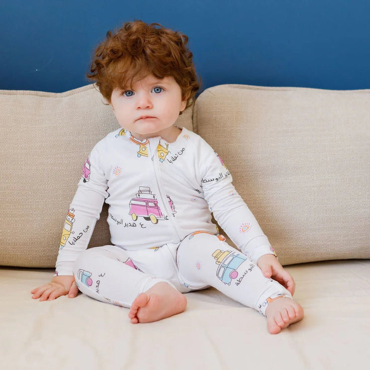 Child wearing a Bosta onesie with colorful graphics sitting on a beige couch.