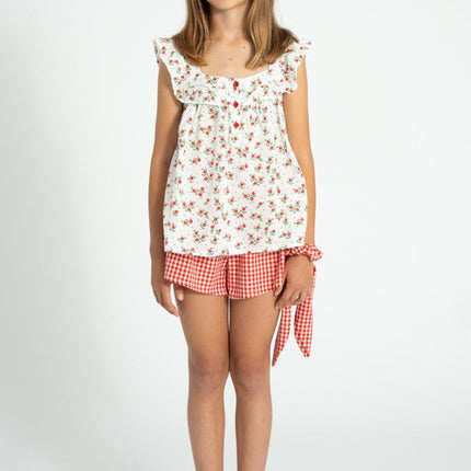 girl wearing floral sleeveless top with red and white checkered shorts