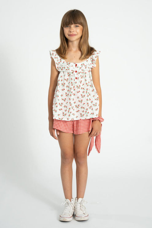 girl wearing floral sleeveless top with red and white checkered shorts