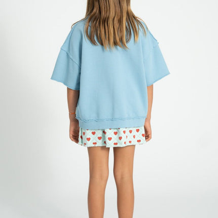 kid wearing light blue skirt with red hearts pattern