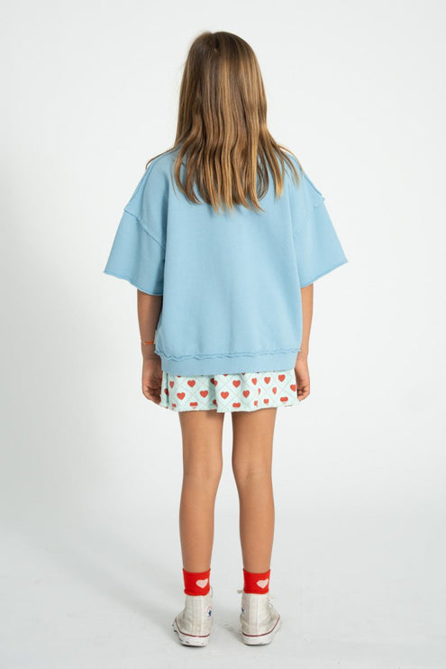 kid wearing light blue skirt with red hearts pattern