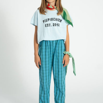 Girl wearing white t-shirt pair with green and blue checkered trouser 