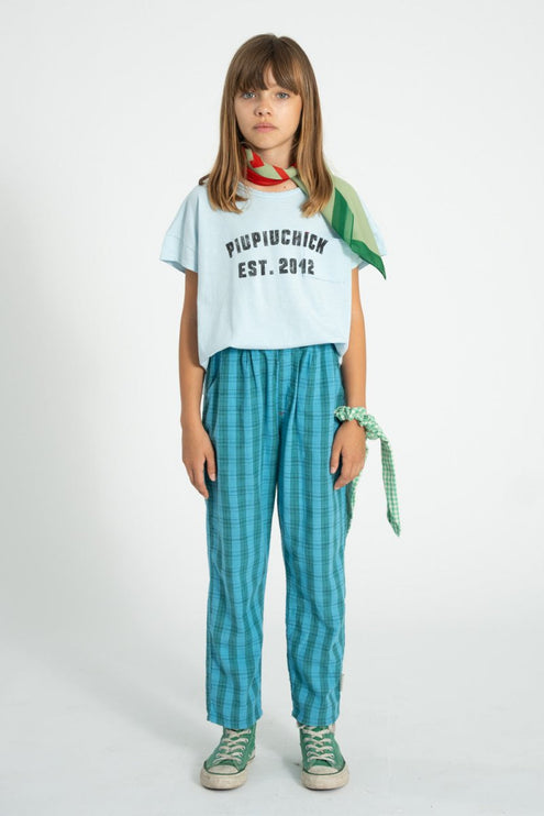 Girl wearing white t-shirt pair with green and blue checkered trouser 