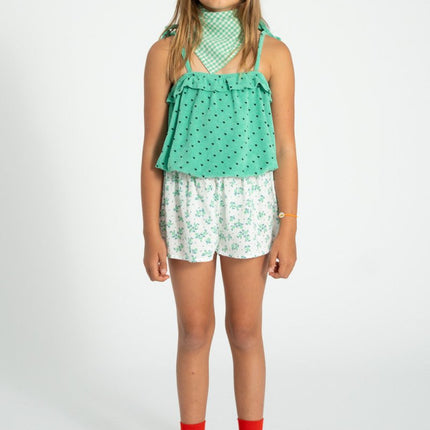 kid wearing green top with white floral shorts