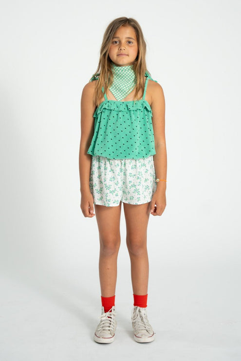 kid wearing green top with white floral shorts