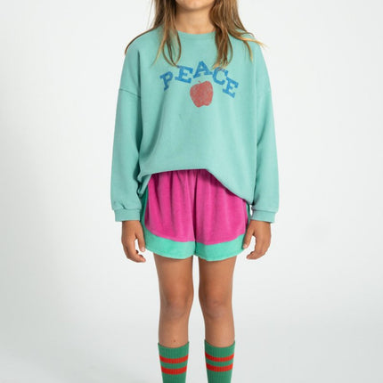 girl wearing turquoise sweatshirt pair with pink and turquoise shorts