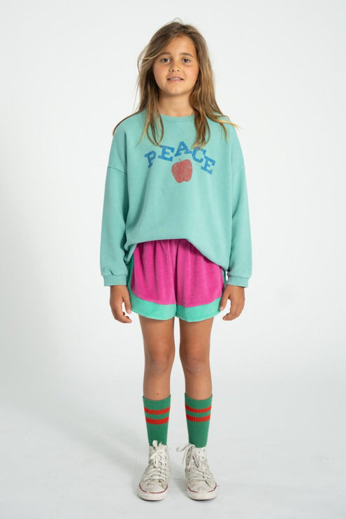 girl wearing turquoise sweatshirt pair with pink and turquoise shorts