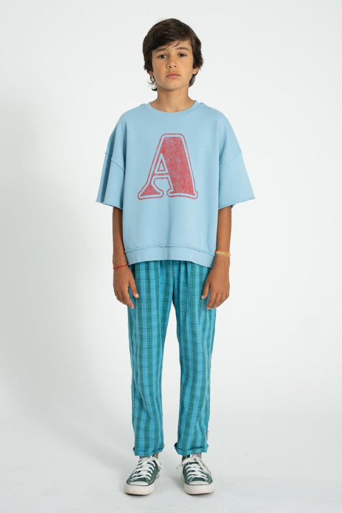 Boy wearing teal oversize shirt paired with blue and green checkered trouser