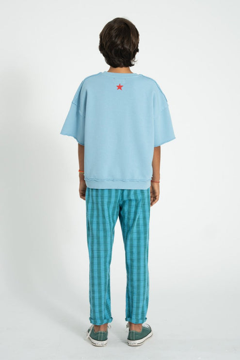 Boy wearing teal oversize shirt with blue and green checkered trouser