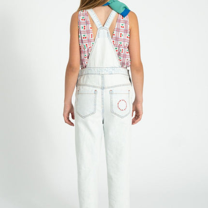 girl wearing cherry print sleeveless top with light blue denim overalls