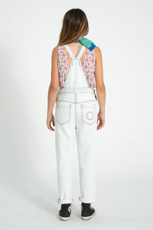 girl wearing cherry print sleeveless top with light blue denim overalls