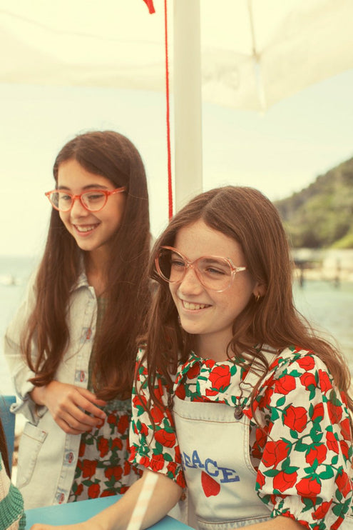 Two young girls wearing blouse with red roses print