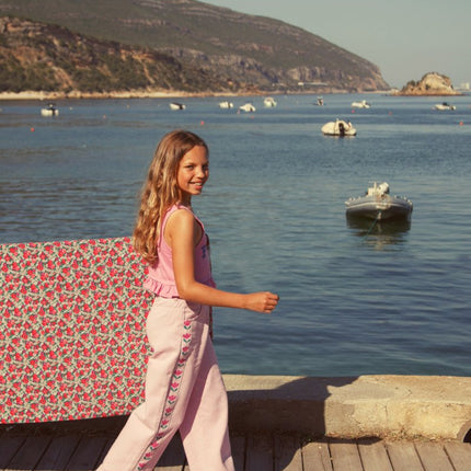 girl walking wearing pink flare trousers with print on the side