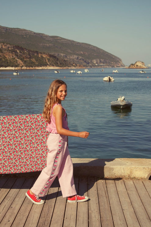 girl walking wearing pink flare trousers with print on the side