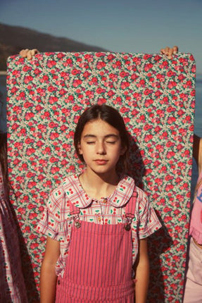 Young girl in a floral dress and pink overalls 