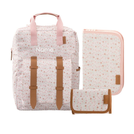 A coordinated bag set featuring a soft pink and white floral backpack with tan straps, a matching zippered pouch, and a small matching wallet. The backpack has a customizable name printed on the front.