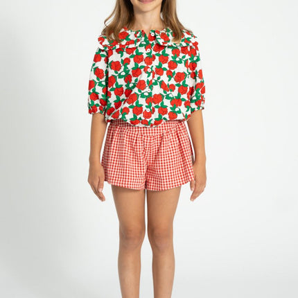 Child wearing sailor collar shirt with red roses print paired with red and white shorts