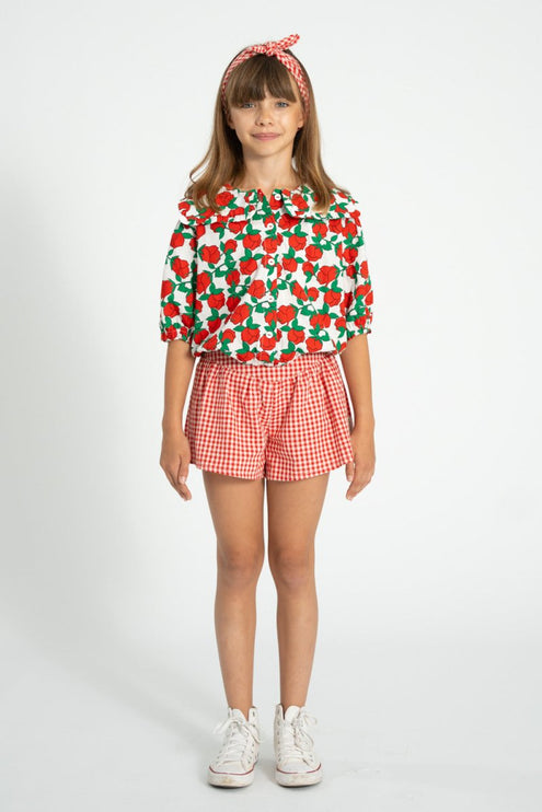 Child wearing sailor collar shirt with red roses print paired with red and white shorts