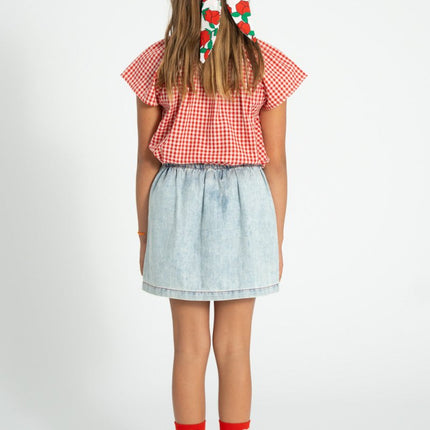 Kid wearing skirt paired with red and white checkered blouse