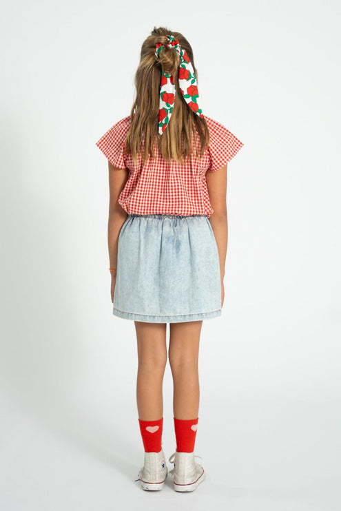 Kid wearing skirt paired with red and white checkered blouse