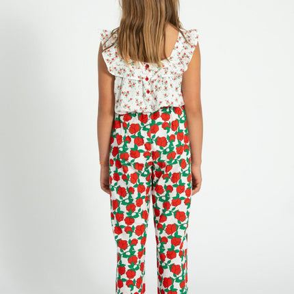 girl wearing a floral top and red and green patterned pants on a white background