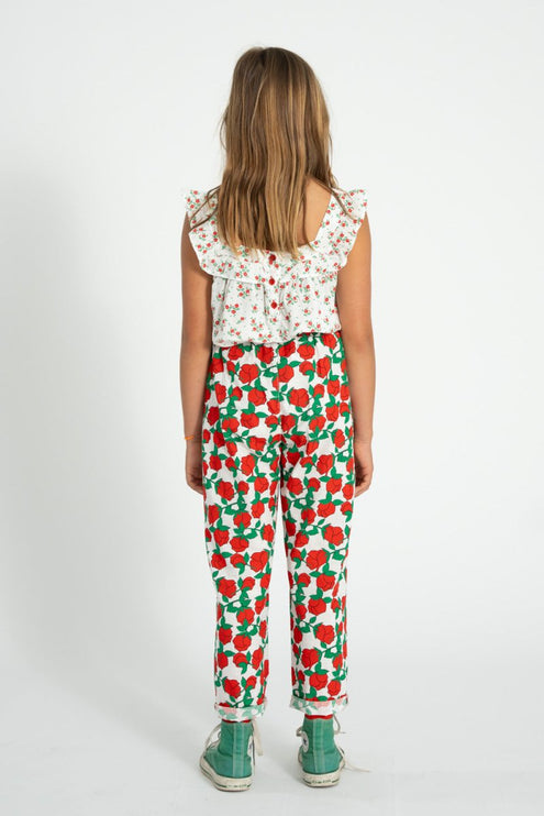 girl wearing a floral top and red and green patterned pants on a white background