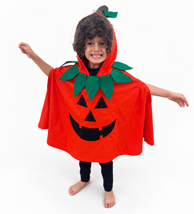 A child wearing a bright orange pumpkin-shaped hooded cape with green leaves and a black jack-o'-lantern face, standing barefoot against a plain white background.