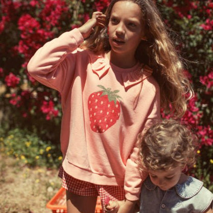 Girl wearing light pink sweatshirt  with collar and strawberry print
