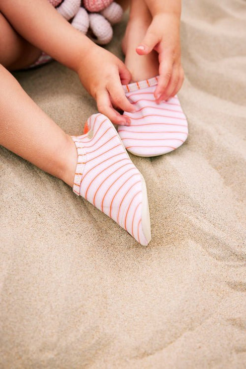 Baby girl wearing stripped cream and peach Swim shoes 