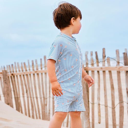Boy wearing striped blue and cream swim suit with Crab print