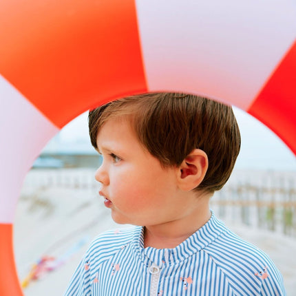 Boy wearing striped blue and cream swim suit with Crab print