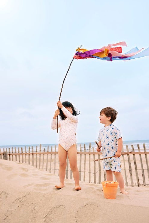 Girl wearing cream longsleeves swim suit with Butterflies print featuring a boy wearing a cream swim suit with blue monkey prints