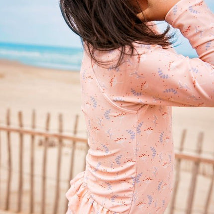 Girl wearing peach tank suit with mimosa print.