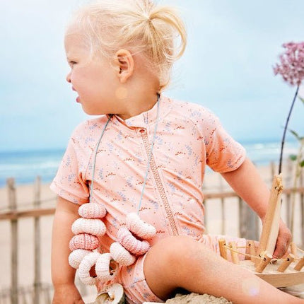 Girl wearing peach swimsuit with mimosa prints