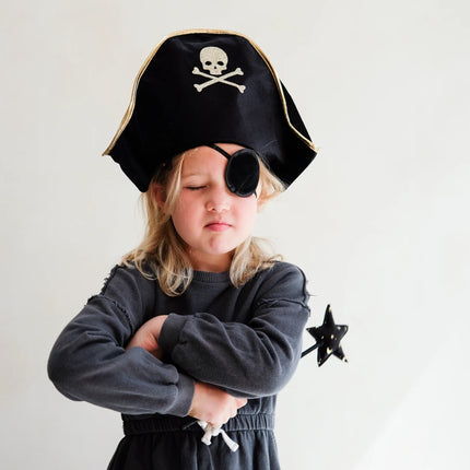 Child wearing a pirate costume with a black hat and eye patch, holding a star-shaped object.