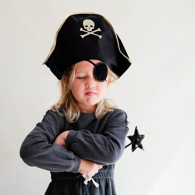 Child wearing a pirate costume with a black hat and eye patch, holding a star-shaped object.