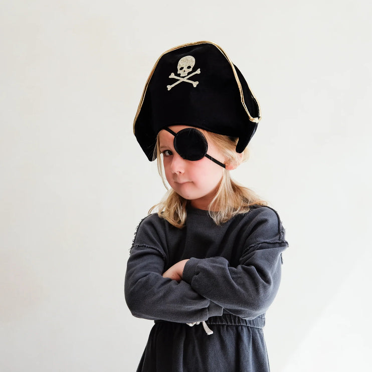 Child wearing a pirate hat and eye patch on a plain background
