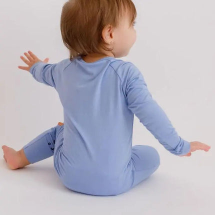 Child wearing a Bahry blue onesie sitting on a white background