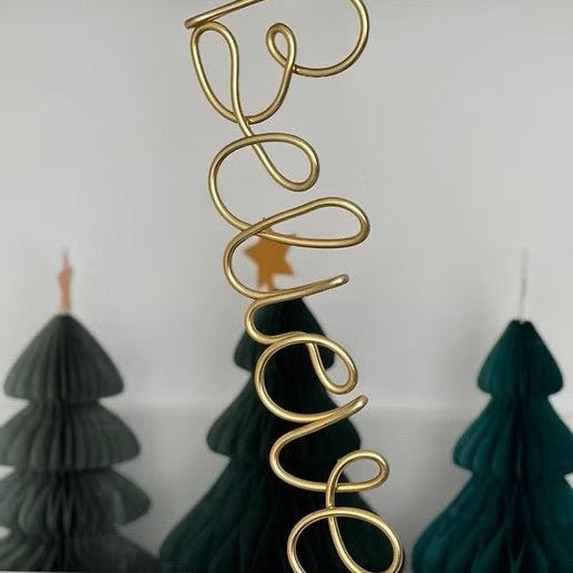 Gold wire ornament spelling 'Believe' on dark green ribbon