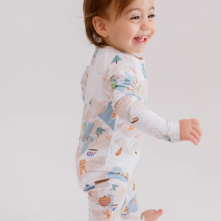 Child wearing a patterned onesie on a plain background