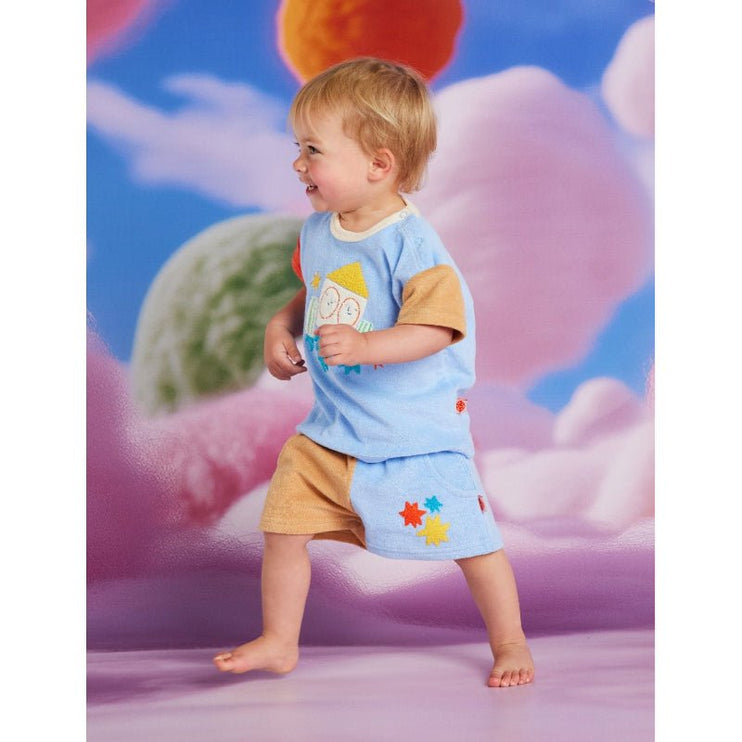 Child wearing a blue shirt and shorts with colorful designs