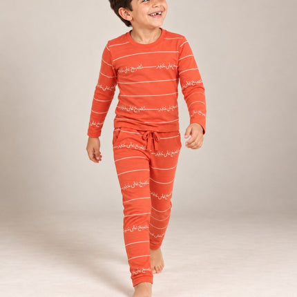 A young boywearing a matching two-piece orange pajama set with white horizontal stripes and Arabic calligraphy print