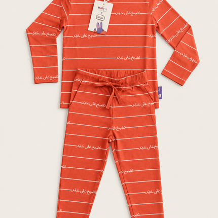 A two-piece children's pajama set featuring a long-sleeve top and matching pants in a vibrant orange-red color, decorated with thin white horizontal stripes and white Arabic calligraphy text. 