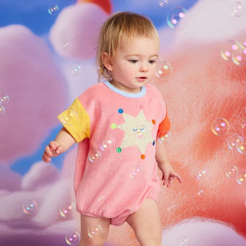 Child wearing a colorful outfit with a cartoon character on a cloud-themed background