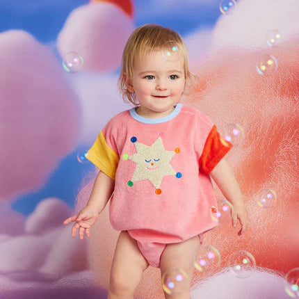 Child wearing a colorful outfit with a star design against a whimsical background