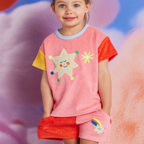 Child wearing a pink and red outfit with colorful star design against a soft, multicolored background