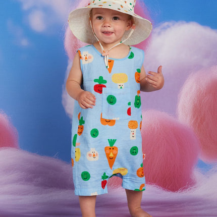 Child wearing a colorful outfit with veggie print patterns and a hat